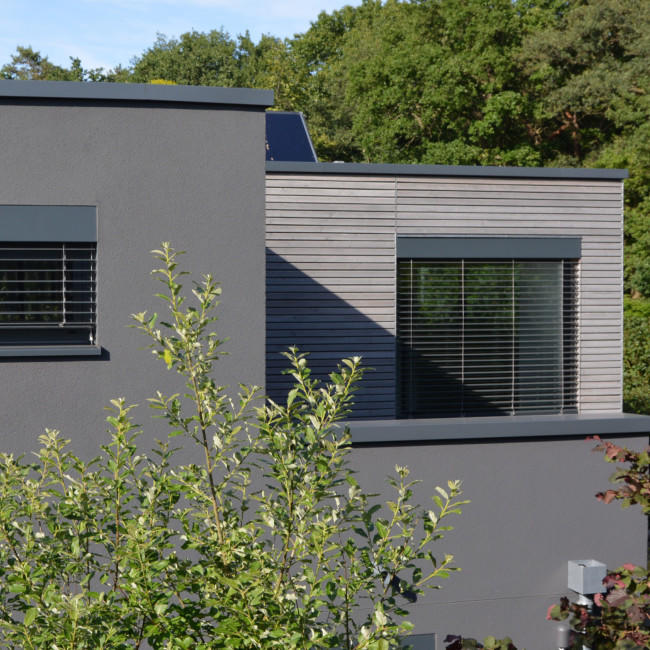 Ein modernes Haus mit Außenfensterbänken und Mauerbrüstungen aus schwarzem Aluminium.